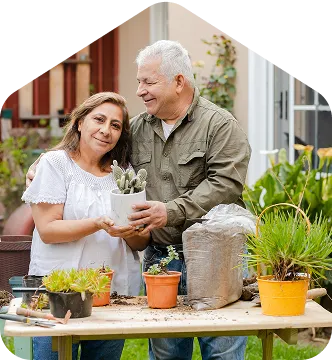 A man and woman standing next to a table with potted plants.