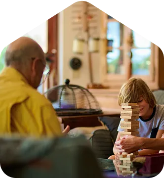 A man and a child playing with a tower of blocks.
