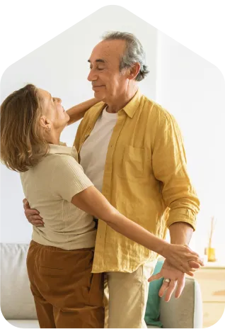 A man and a woman dancing together in a living room.